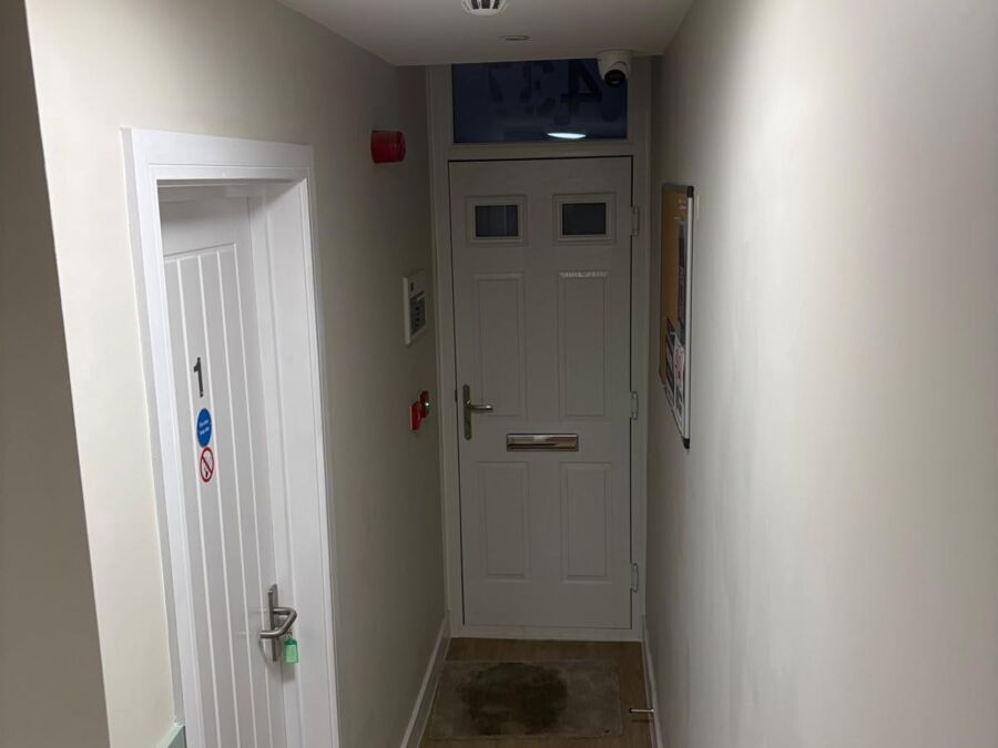 Residential entrance hallway featuring white painted walls, ceiling mounted flush light fitting, smoke detector, and laminate flooring